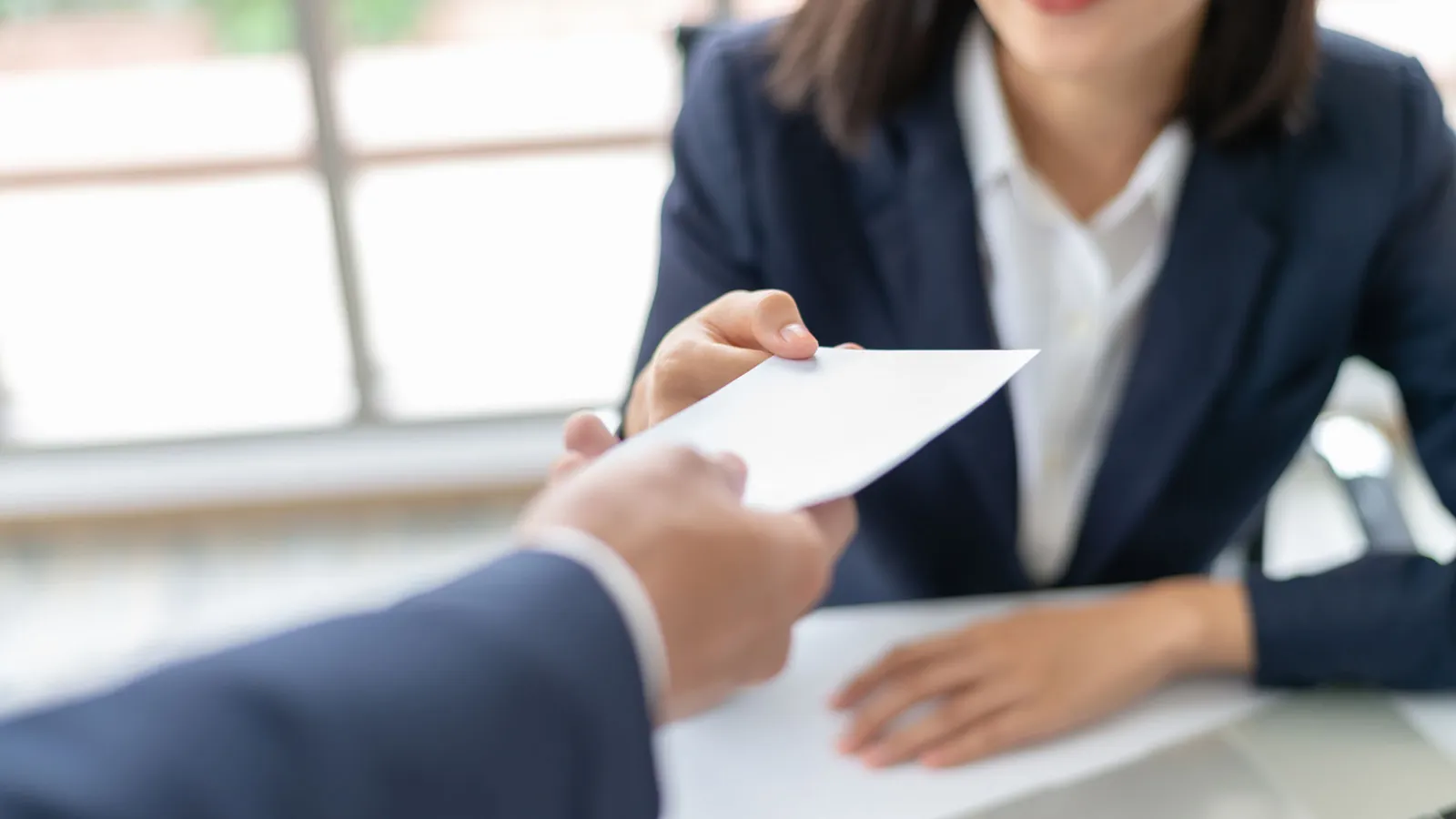 photo of a business man handing a business woman a check.