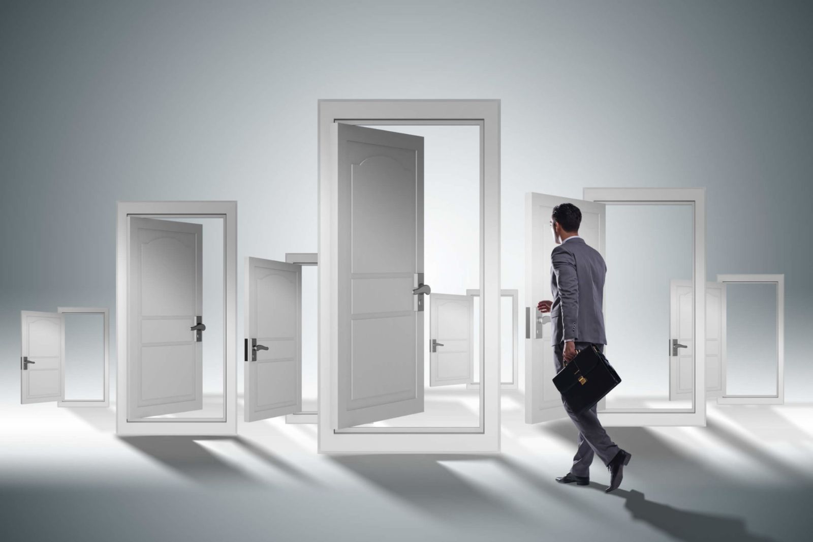 A business person choosing from several freestanding doors and walking through one.