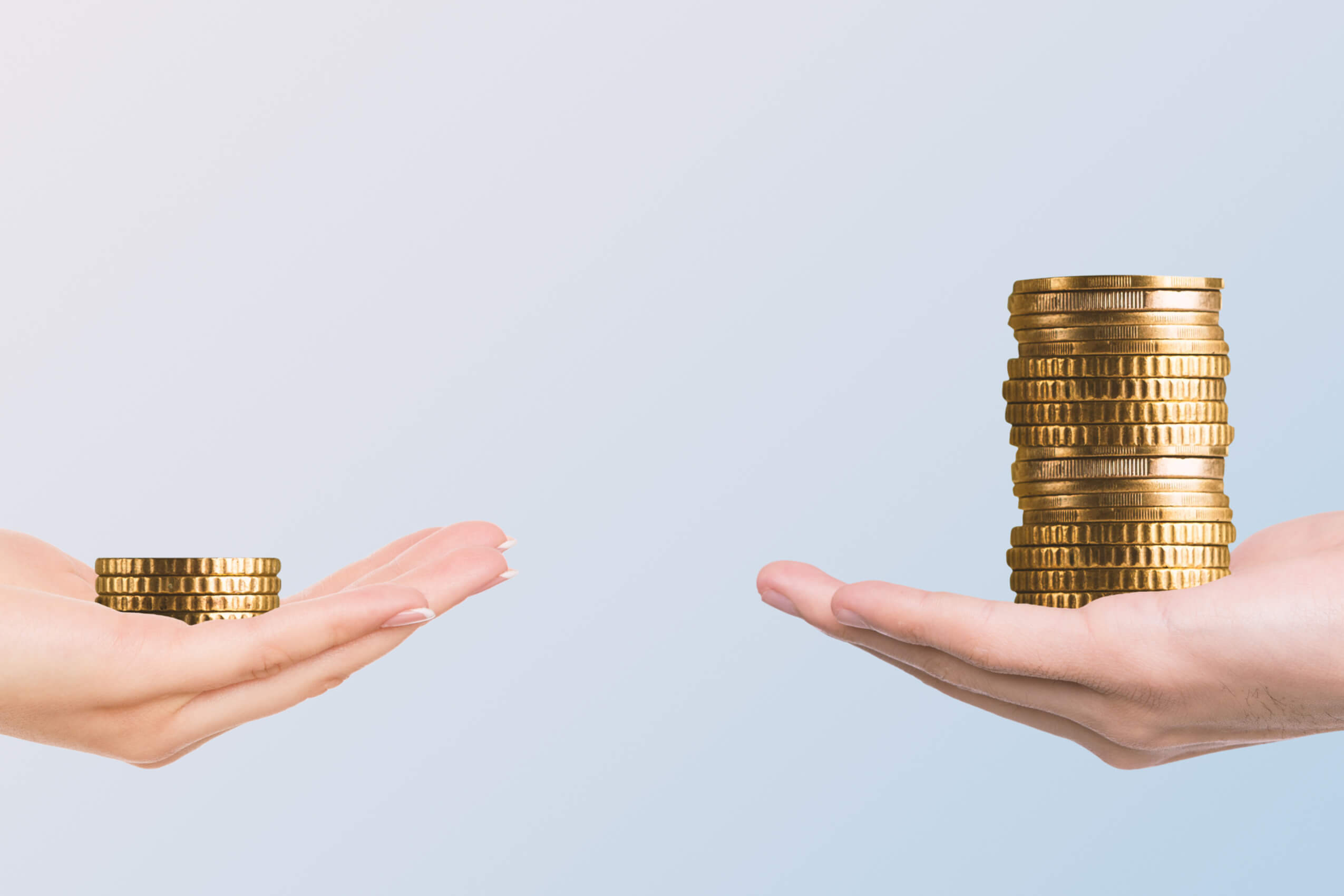 Two hands holding stacks of coins. One stack is much taller than the other.