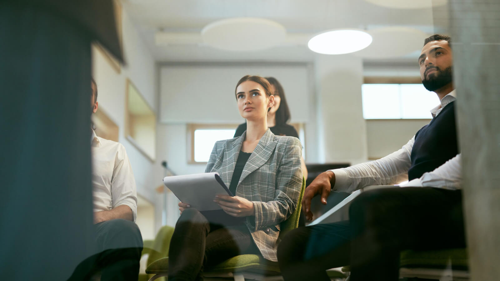 Photo of two employees sitting in chairs watching a work presentation.