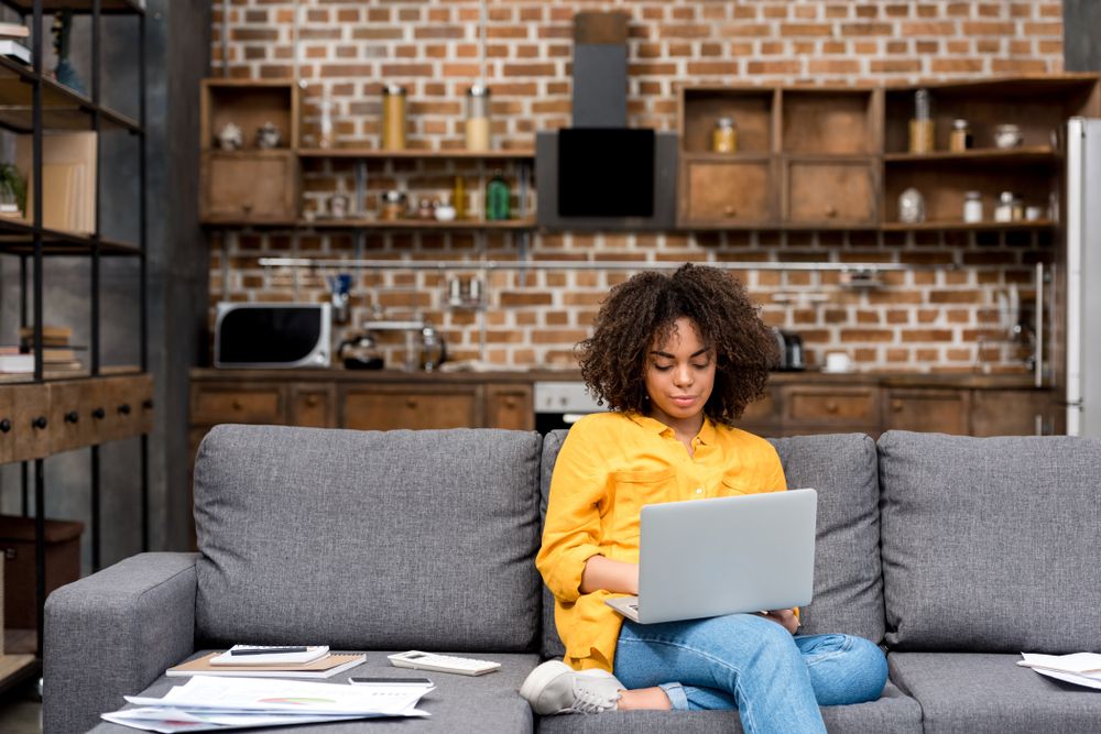 Person sitting on their couch working on a laptop.