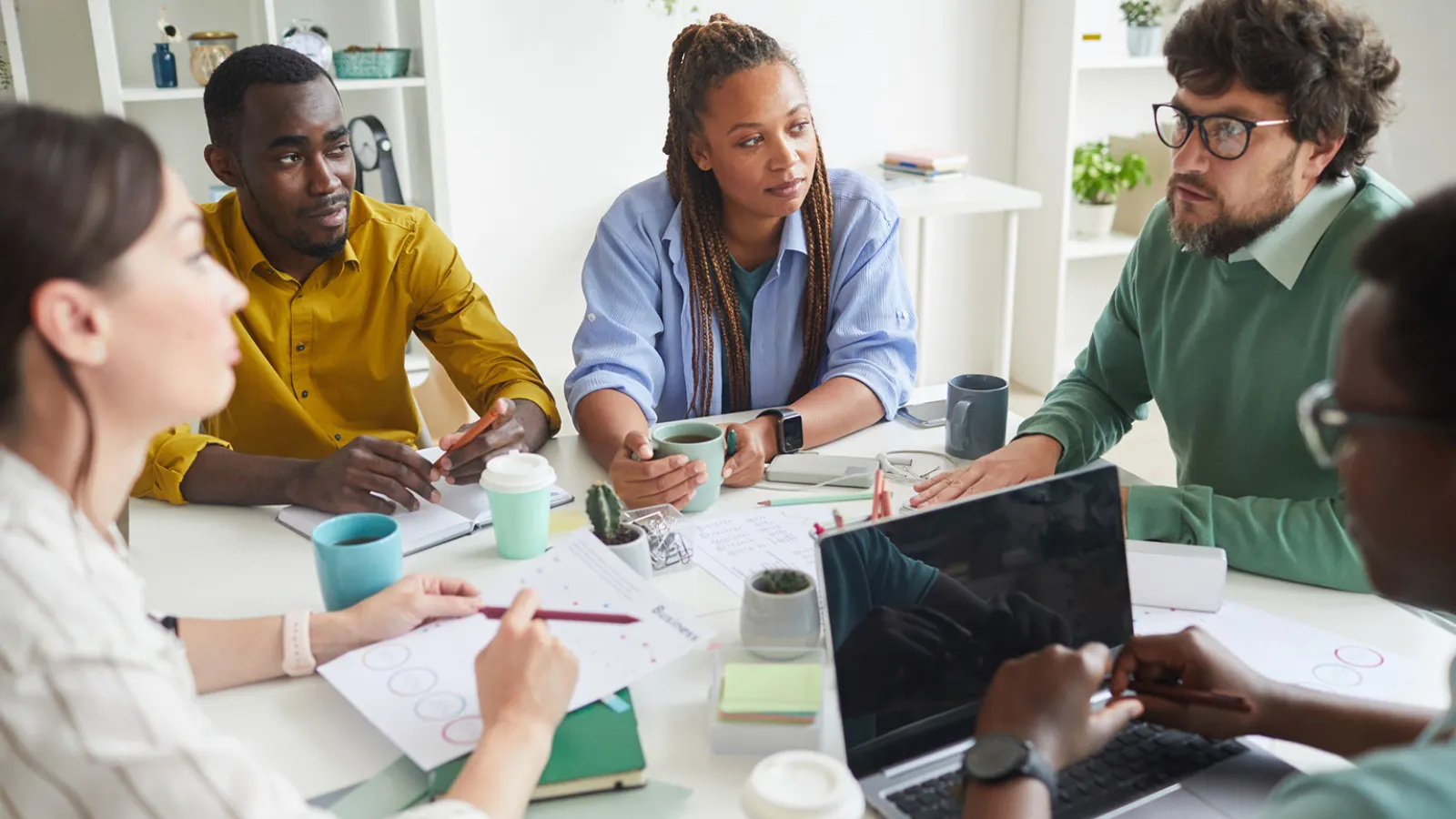 Photo of a diverse group of workers having a meeting around a table.