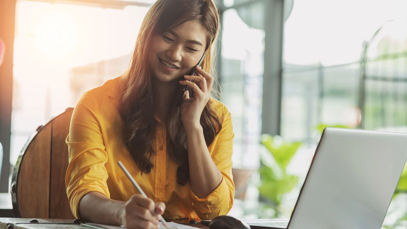 Business person talking on the phone while working at a laptop.