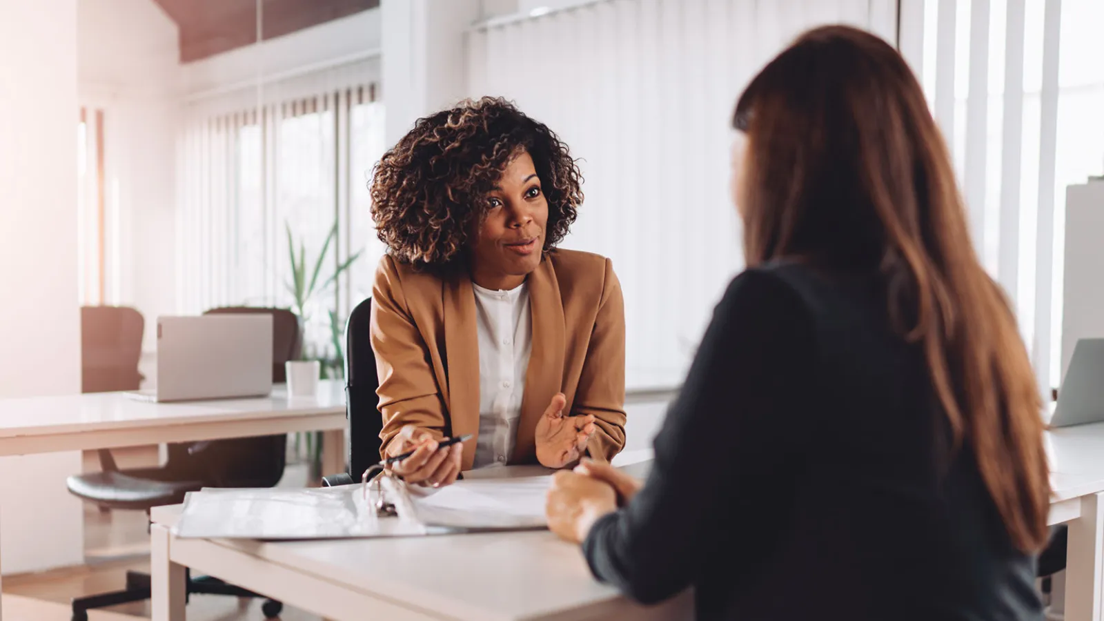 Photo of a hiring manager interviewing a job candidate sitting at a desk.