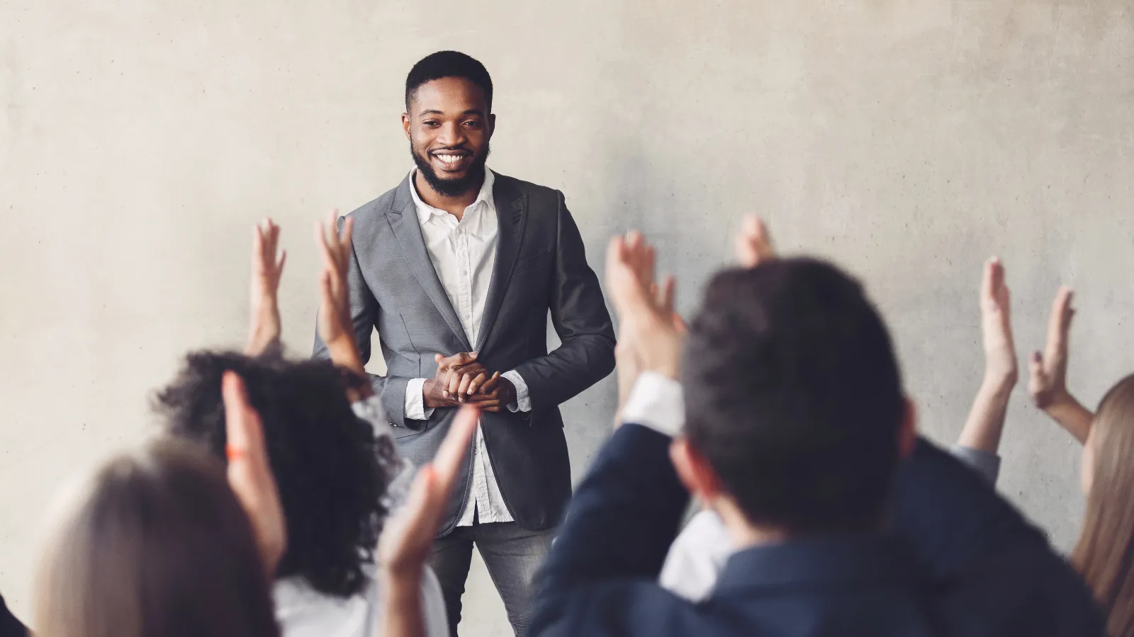 Photo of a business man talking to a group of colleagues who are clapping.