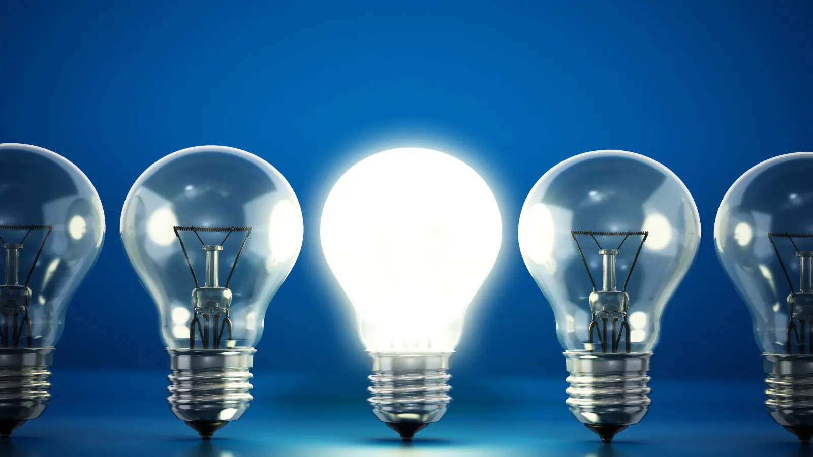 Graphic of five light light bulbs against a blue background. The center bulb is lit to symbolize a bright idea.