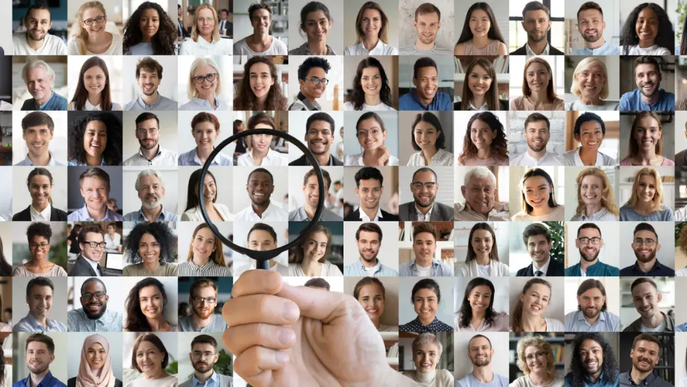 A collage of professional headshots with a hand holding a magnifying glass over top.
